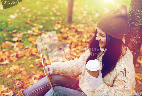 Image of woman with tablet pc and coffee in autumn park