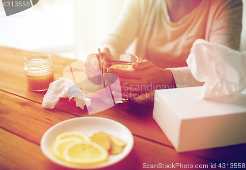 Image of ill woman drinking tea with lemon and honey