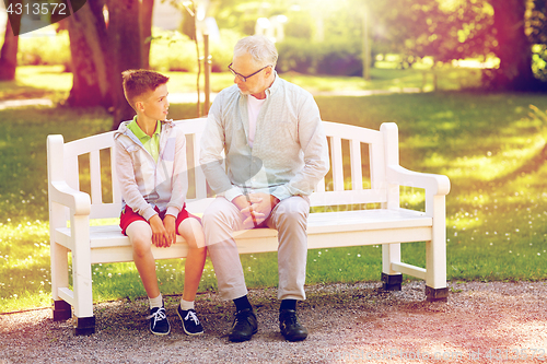 Image of grandfather and grandson talking at summer park