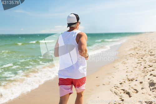 Image of happy man running along summer beach