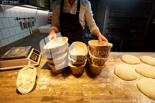 Image of baker with baskets for bread dough at bakery