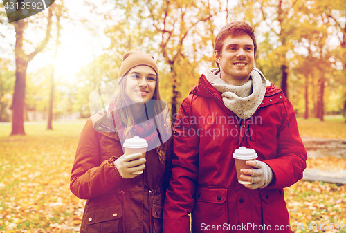 Image of happy couple with coffee walking in autumn park