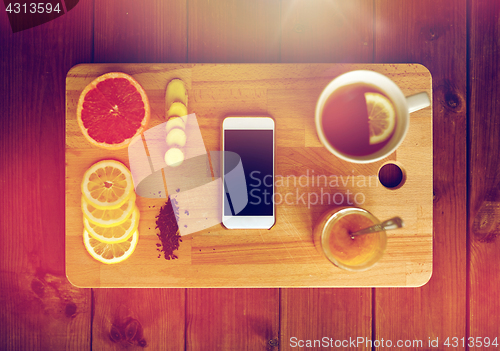 Image of smartphone with cup of lemon tea, honey and ginger