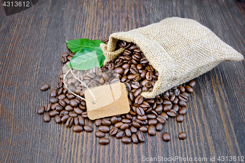 Image of Coffee black grain with tag and leaf in bag on board