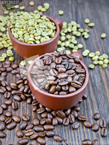 Image of Coffee black and green grains in cups on board