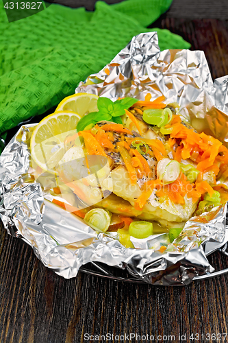 Image of Pike with leeks and carrots in foil on board