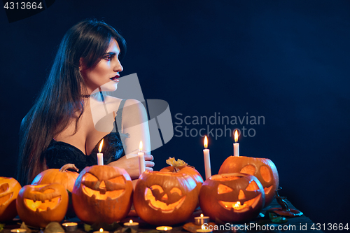Image of Beautiful witch with Halloween pumpkins