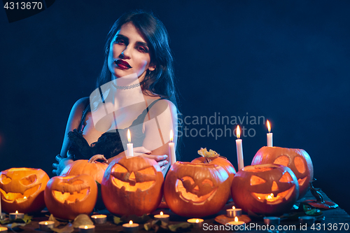 Image of Beautiful witch with Halloween pumpkins