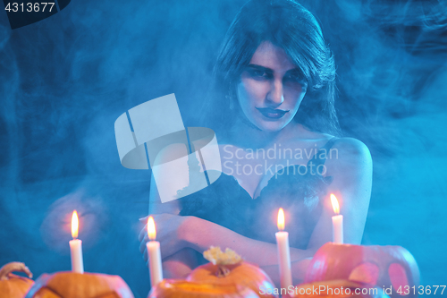 Image of Beautiful witch with Halloween pumpkins