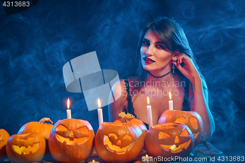 Image of Beautiful witch with Halloween pumpkins