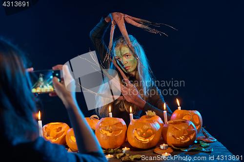 Image of Girl capturing photo of Halloween woman with her smart phone