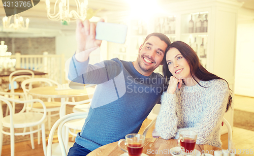 Image of couple taking smartphone selfie at cafe restaurant