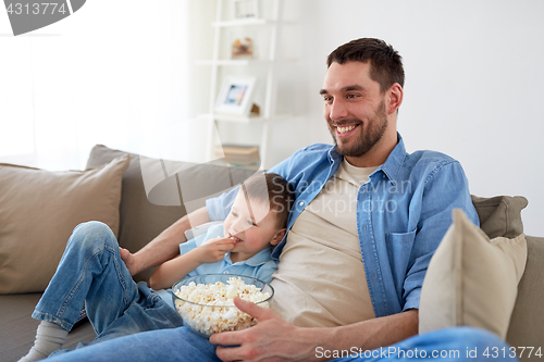 Image of father and son with popcorn watching tv at home