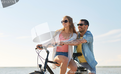 Image of happy young couple riding bicycles at seaside