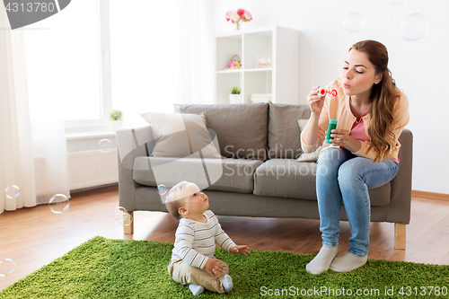 Image of mother with soap bubbles playing with baby at home