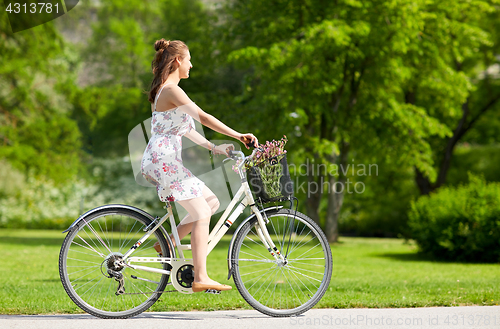 Image of happy woman riding fixie bicycle in summer park