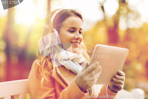 Image of woman with tablet pc and headphones in autumn park