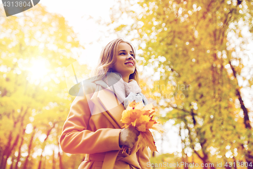Image of beautiful woman with maple leaves in autumn park