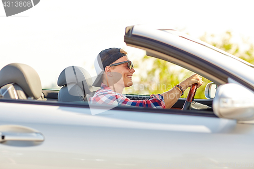 Image of happy young man in shades driving convertible car