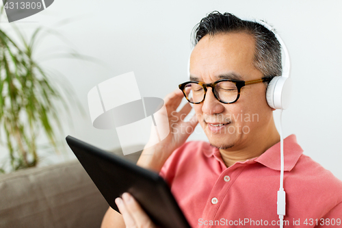 Image of man with tablet pc and headphones at home