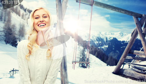 Image of smiling young woman in winter earmuffs and sweater