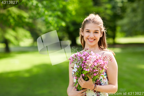 Image of happy young woman with flowers in summer park