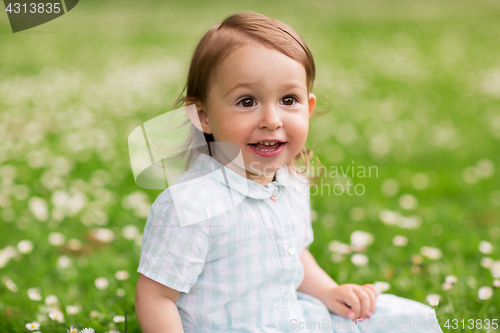 Image of happy baby girl on green summer field