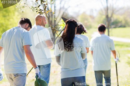 Image of happy volunteers with seedlings and garden tools