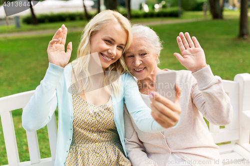 Image of daughter and senior mother taking selfie at park