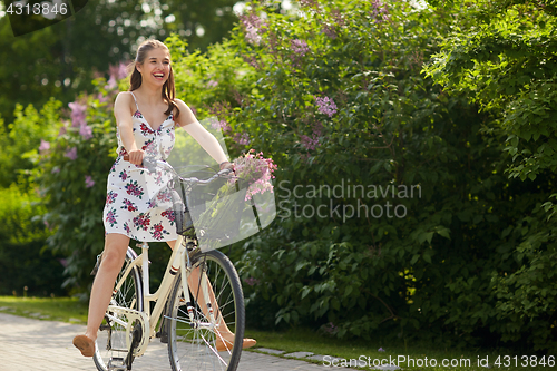 Image of happy woman riding fixie bicycle in summer park