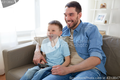 Image of father and son with remote watching tv at home