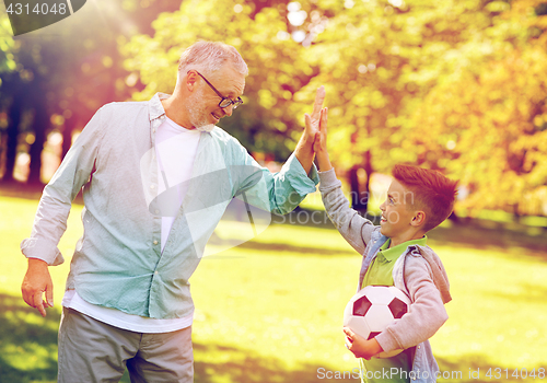 Image of old man and boy with soccer ball making high five