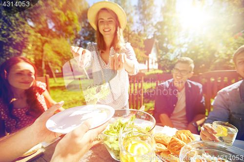 Image of happy friends having dinner at summer garden party