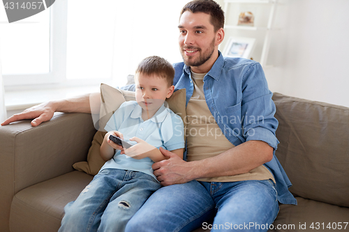 Image of father and son with remote watching tv at home