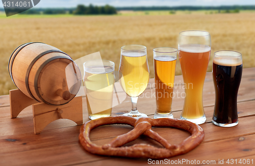 Image of beer glasses, barrel and pretzel over cereal field