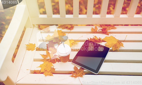 Image of tablet pc and coffee cup on bench in autumn park