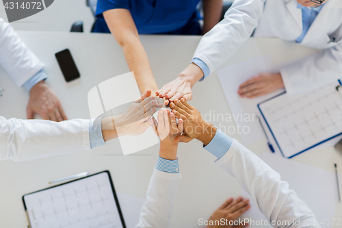 Image of group of doctors making high five at table