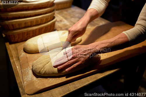 Image of baker making bread and cutting dough at bakery