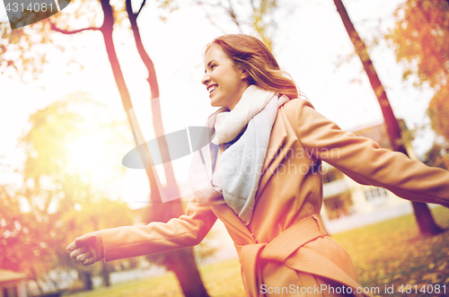 Image of beautiful happy young woman walking in autumn park