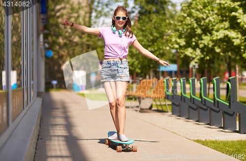 Image of happy teenage girl in shades riding on longboard