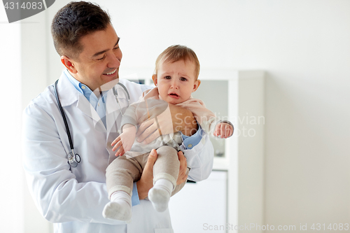 Image of happy doctor or pediatrician with baby at clinic