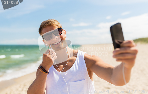 Image of man with smartphone taking selfie on summer beach