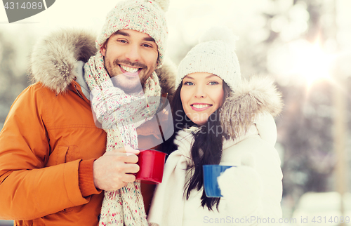 Image of happy couple with tea cups over winter landscape