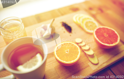 Image of ginger tea with honey, citrus and garlic on wood