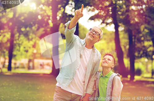 Image of grandfather and boy pointing up at summer park