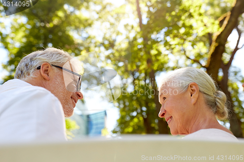 Image of happy senior couple sitting on bench at park