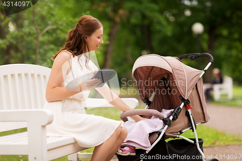 Image of happy mother with tablet pc and stroller at park