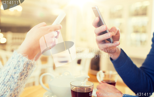 Image of close up of couple with smartphones at cafe