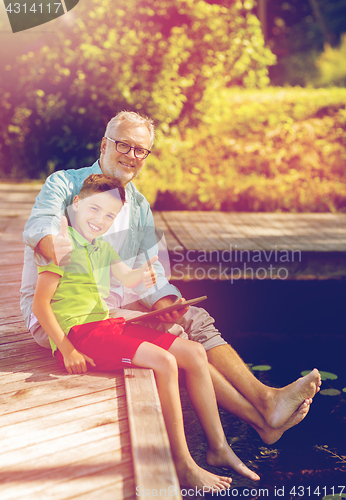 Image of grandfather and boy with tablet pc on river berth