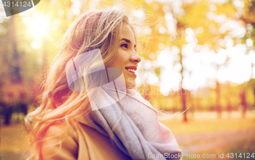 Image of beautiful happy young woman smiling in autumn park